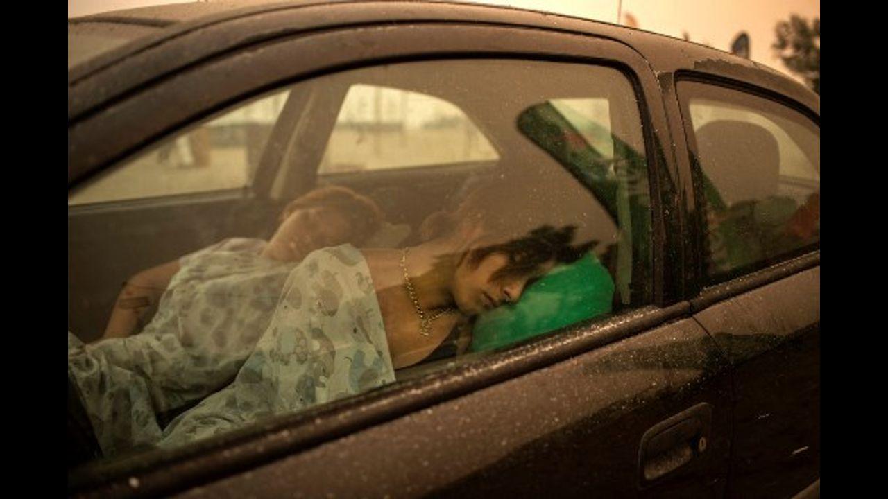 A woman sleeps in her car on the beach as wildfire rages in Pefki village on Evia (Euboea) island, second largest Greek island. Hundreds of Greek firefighters fought desperately to control wildfires on the island of Evia that have charred vast areas of pine forest, destroyed homes and forced tourists and locals to flee.